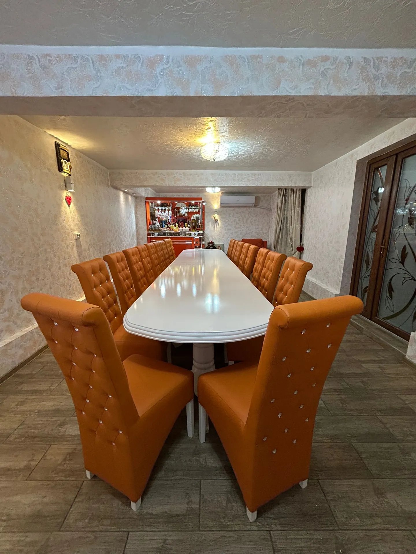 Sala de mese cu masă lungă și scaune capitonate